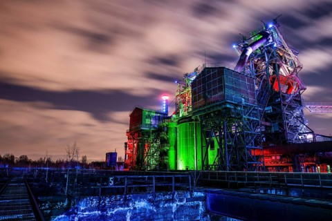 Industrial complex at dusk with colorful lighting and moving cloudy sky, Duisburg Nord Landscape