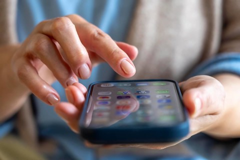Mobile phone, in a user's hand, screen with various apps