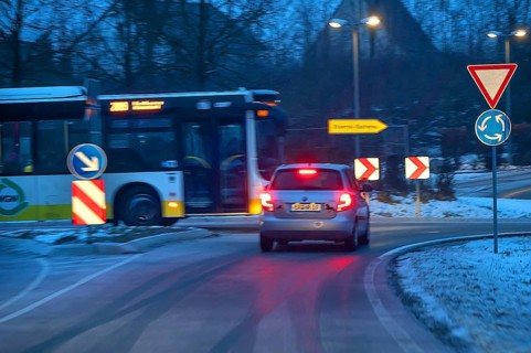Car and bus at roundabout during night snow flurries, Eckental, Middle Franconia, Bavaria, Germany
