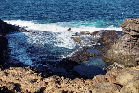 Coastal landscape with rocks in the foreground and riverbank surf in the background, Playa Blanca