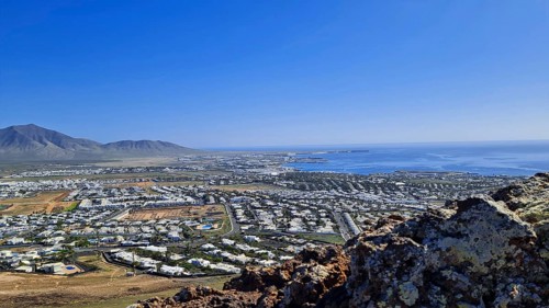 Panorama of the coastal town (Playa Blanca) with sea view and mountains under a clear sky, Playa