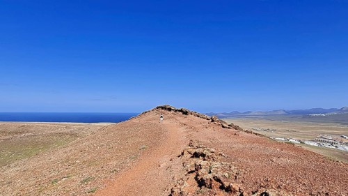 Narrow path on the summit of the Montana Roja volcano with views of the sea under a clear blue sky,