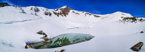 Alpine mountain panorama in snow on Schlappoldsee with wooden bench on Fellhorn in spring in the