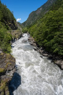 Wild flowing river in a mountainous, wooded landscape under blue sky, Enguri River near Khaishi,