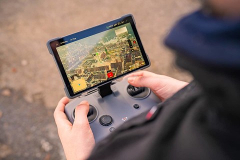 A person holds a remote control with screen for drone control, fiber optic groundbreaking,