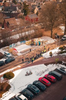 Aerial view of a street scene with people and cable drums in the snow, fiberglass groundbreaking,
