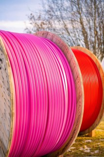 Large, coloured cable drums with pink and red cables outdoors, fibreglass groundbreaking,