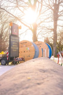 Construction site with cable rolls and a sign in warm sunlight, fiberglass groundbreaking,