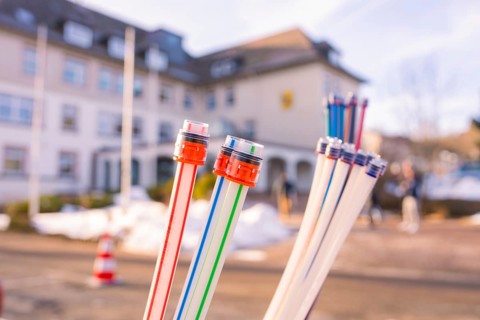 Colourful bundles of cables in front of a snow-covered building with people, fibreglass