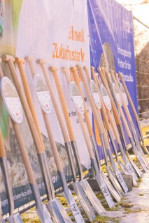 Row of spades standing in front of advertising banners on a sunny winter day on a building site,