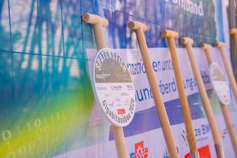 Row of shovels in front of an information poster at a symbolic event, fiberglass groundbreaking,