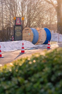 Cable drums and traffic cones on a construction site in the snow at sunrise, fibreglass