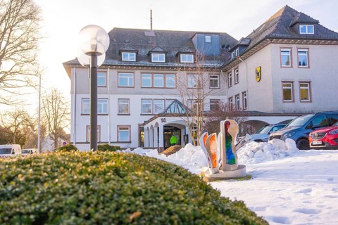A snowy building with sculptures and parked cars in winter light, fibreglass groundbreaking,