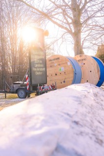 Cable rolls and a construction site sign along a snowy road when the sun is low, fibreglass