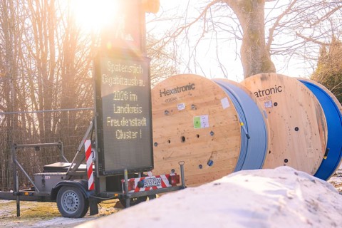 Two rolls of cable next to a glowing construction site sign in a winter environment, fibreglass
