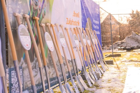 Several spades in front of colorful banners on a snow-covered building site in the winter sun,