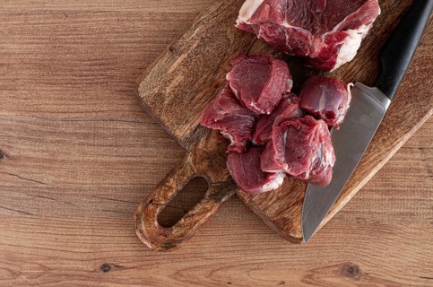 Raw beef meat, sliced on a cutting board, with a knife, no spices, no herbs, top view, wooden