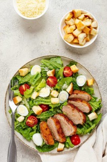 Caesar salad, with duck breast, on a light plate, on a light background, homemade, no people