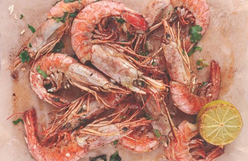 Juicy grilled shrimp, placed on a baking sheet lined with parchment paper, garnished with herbs and