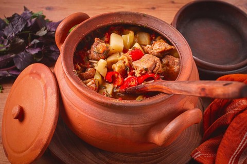 Chanakhi, a Georgian dish. in a clay pot, on a wooden table, stewed meat with vegetables, homemade,