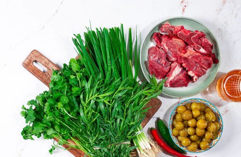 Ingredients for cooking chakapuli, canned tkemali, meat, herbs Georgian cuisine, top view