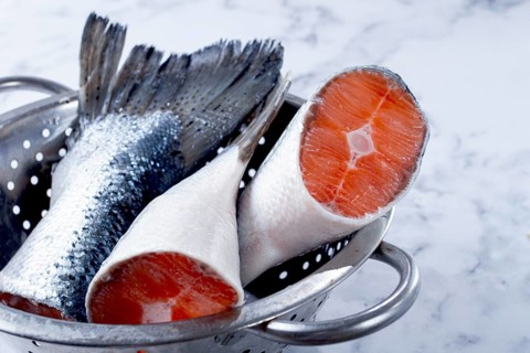Fish tails are placed in a colander on a marble counter. The colander allows water to drain away