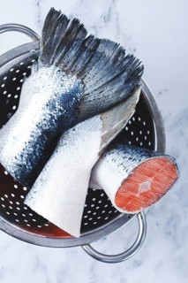 Fish tails are placed in a colander on a marble counter. The colander allows water to drain away