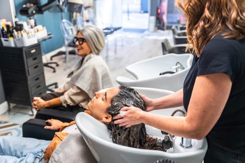 Hairstylist giving a customer a relaxing hair wash and massage at the shampoo station in a modern