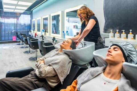 Hairdresser washing client's hair at a modern salon basin, two women enjoying a relaxing,