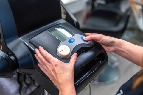 Hairdresser hands adjusting controls on a modern hair treatment machine, delivering professional