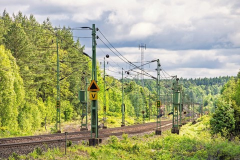Electric railway line with overhead line in a deciduous forest in spring, Sweden