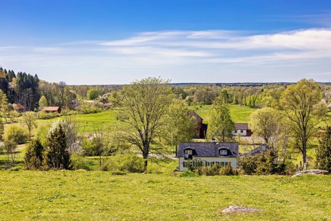 Beautiful landscape view with meadows and fields and residential houses in the countryside on a