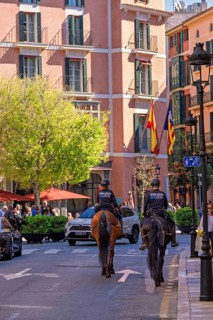 Mounted police officers on horses on a city street with people and cars, Palma de Mallorca,