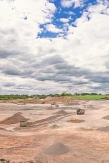 View of an open pit mine with truck and heavy machinery and gravel piles