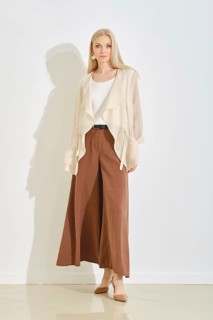 A model displays a fashionable outfit featuring wide, brown pants paired with a lightweight cream