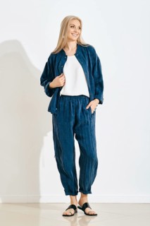 Smiling woman stands in a studio wearing a comfortable outfit, consisting of a matching jacket and