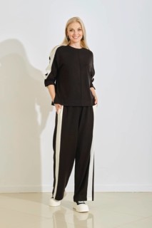 A woman stands confidently in a black and white athletic outfit with pockets, showcasing a modern