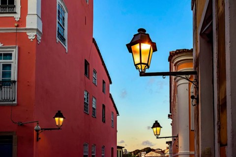 Facades of old houses illuminated by lanterns during sunset on the streets of Pelourinho in