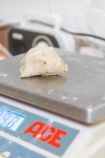 Weighing a small portion of dough on a digital scale in a bakery environment, baking rolls,