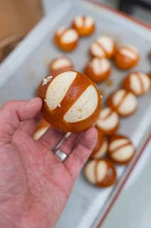 Simple pretzel held in hand with salt, more in the background, baking rolls, Haselstaller Hof,