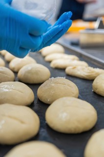 Baker covers dough pieces with white matter, bake rolls, Haselstaller Hof, Gechingen, Germany