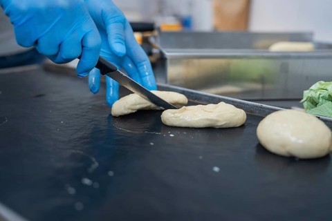 A baker shapes and cuts dough with a knife on a black surface, bake rolls, Haselstaller Hof,