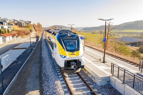 Modern train at the station, surrounded by rural architecture and extensive landscape, test run on
