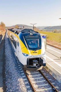Front view of a modern train at the station, surrounded by hilly landscape, test run on the new
