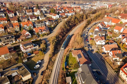 Aerial view of a city with red roofs and a train on rails, test run on the new Hermann-Hesse