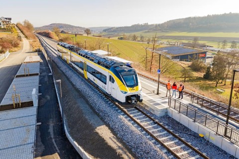 Train on the platform, landscape with hilly surroundings and people on the track, test run on the