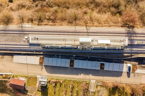Aerial view of a train station with train tracks surrounded by trees and vegetation, test run on