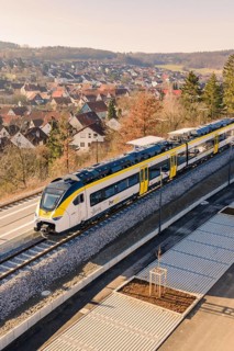 Modern train on rails near a settlement with typical roof houses and nature, test run on the new