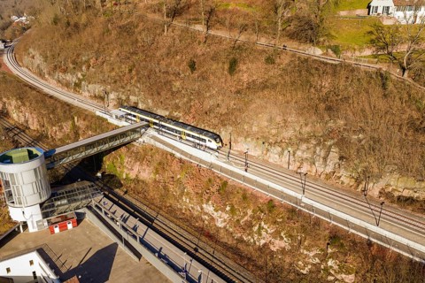 A train crosses a footbridge on elevated tracks in autumn surroundings, test run on the new