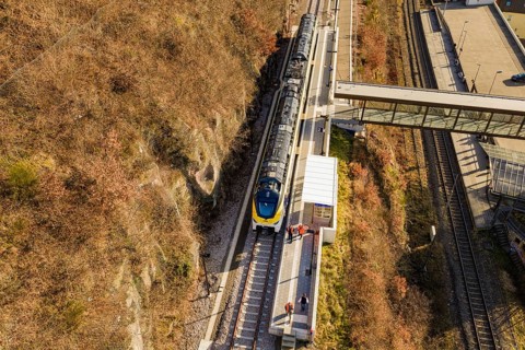 Aerial view of a train on railroad tracks with autumn landscape in the background, test run on the